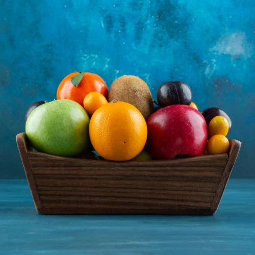 Fruit Bowl A wooden bowl filled with assorted fresh fruits on a blue background.